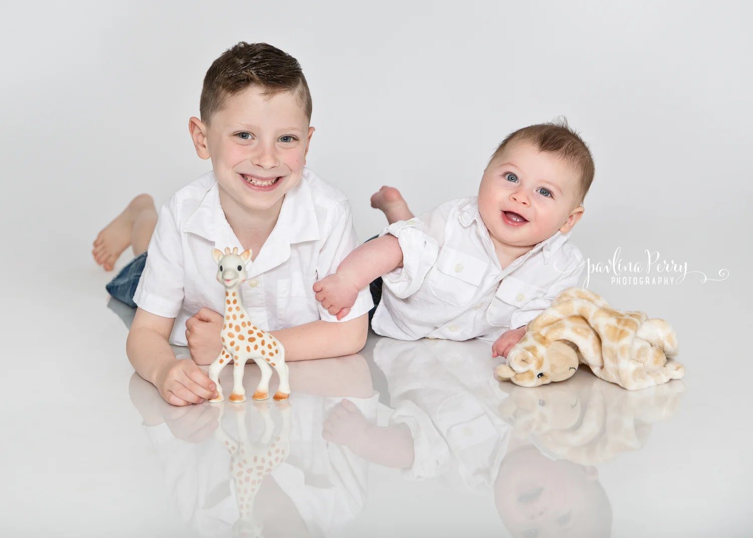 Two young brothers smiling with toys in a bright studio
