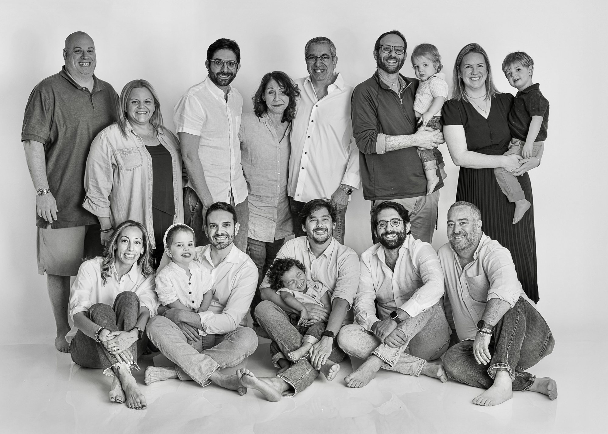 Black-and-white studio portrait of an extended family gathered together, with adults standing and adults and children seated on the floor