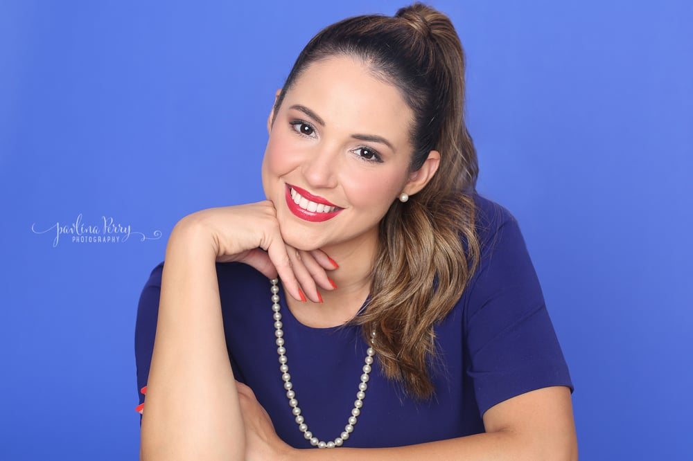 Smiling woman in blue with pearls against a blue studio background