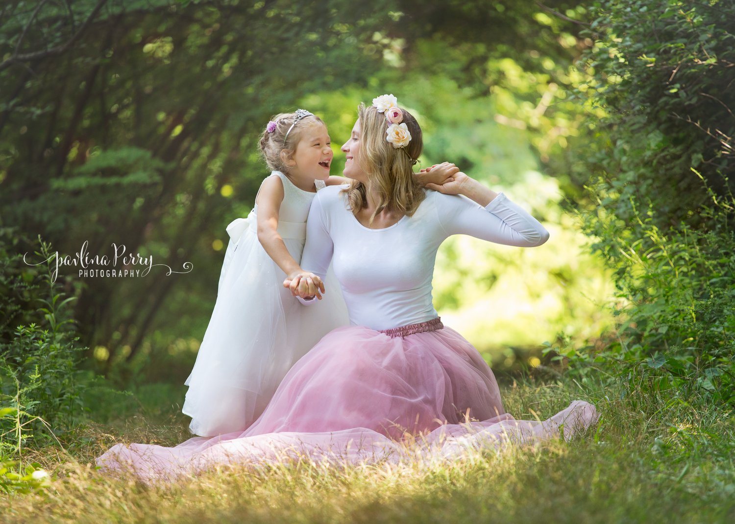 Mother and daughter laughing together in a sunlit woodland setting